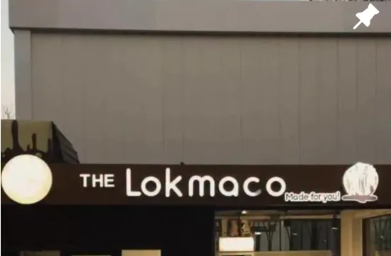 The Lokmaco kafesining peshtoqi — oltin yorug'likdagi 'THE Lokmaco' yozuvi